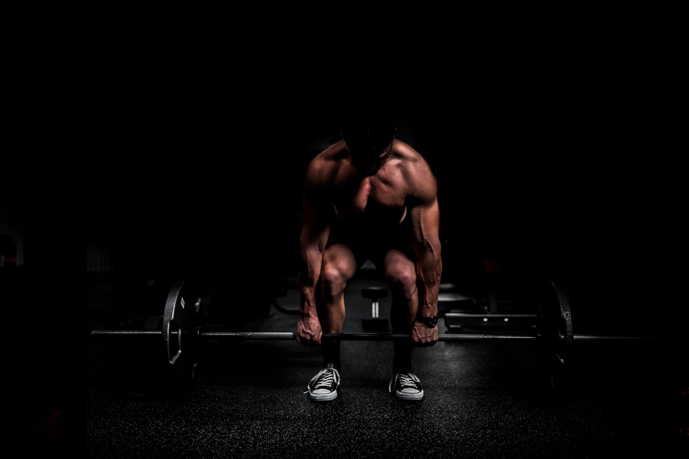 Man deadlifting in a dark room
